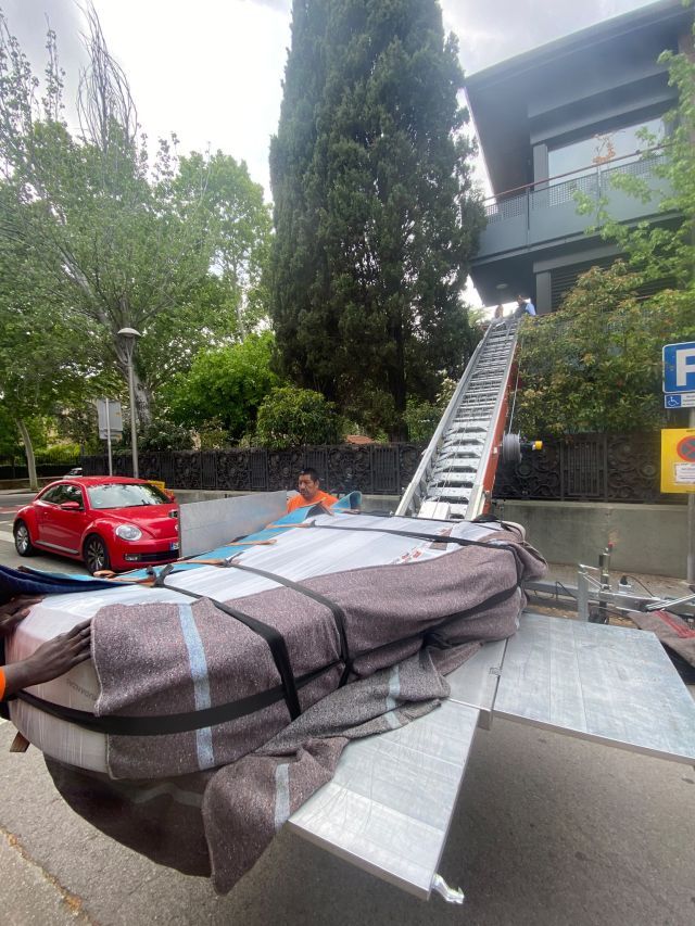 	Piano de cola embalado siendo trasladado con grúa telescópica hasta un balcón