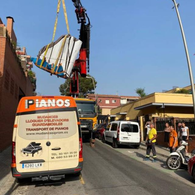 traslado de piano de cola negro con patas desmontadas, siendo introducido en un camión con rampa de seguridad