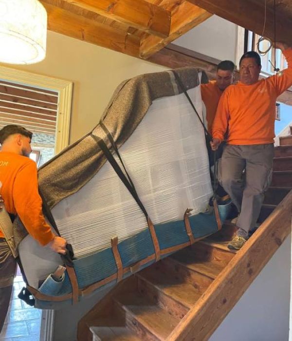 Equipo profesional llevando un piano de cola por escalera complicada para ser trasportado a su lugar de destino
