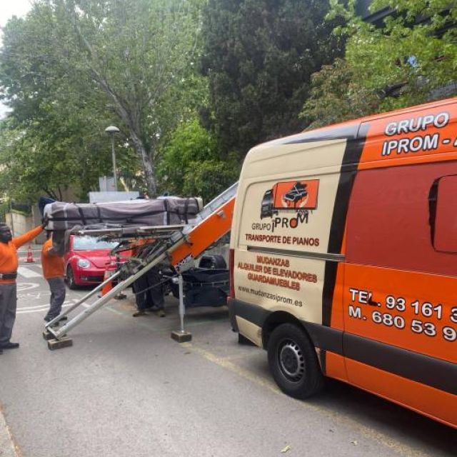 equipo introduciendo un piano de pared en furgoneta para asegurarlo y trasladarlo a destino